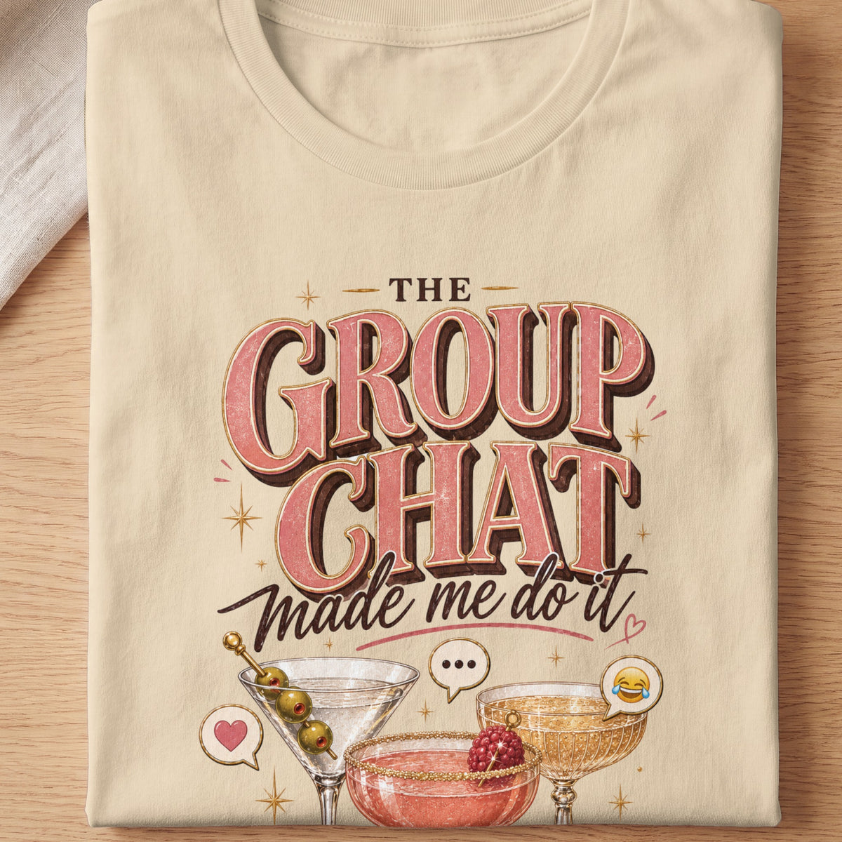 "The Group Chat Made Me Do It" text with cocktails and emojis on a tan t-shirt.