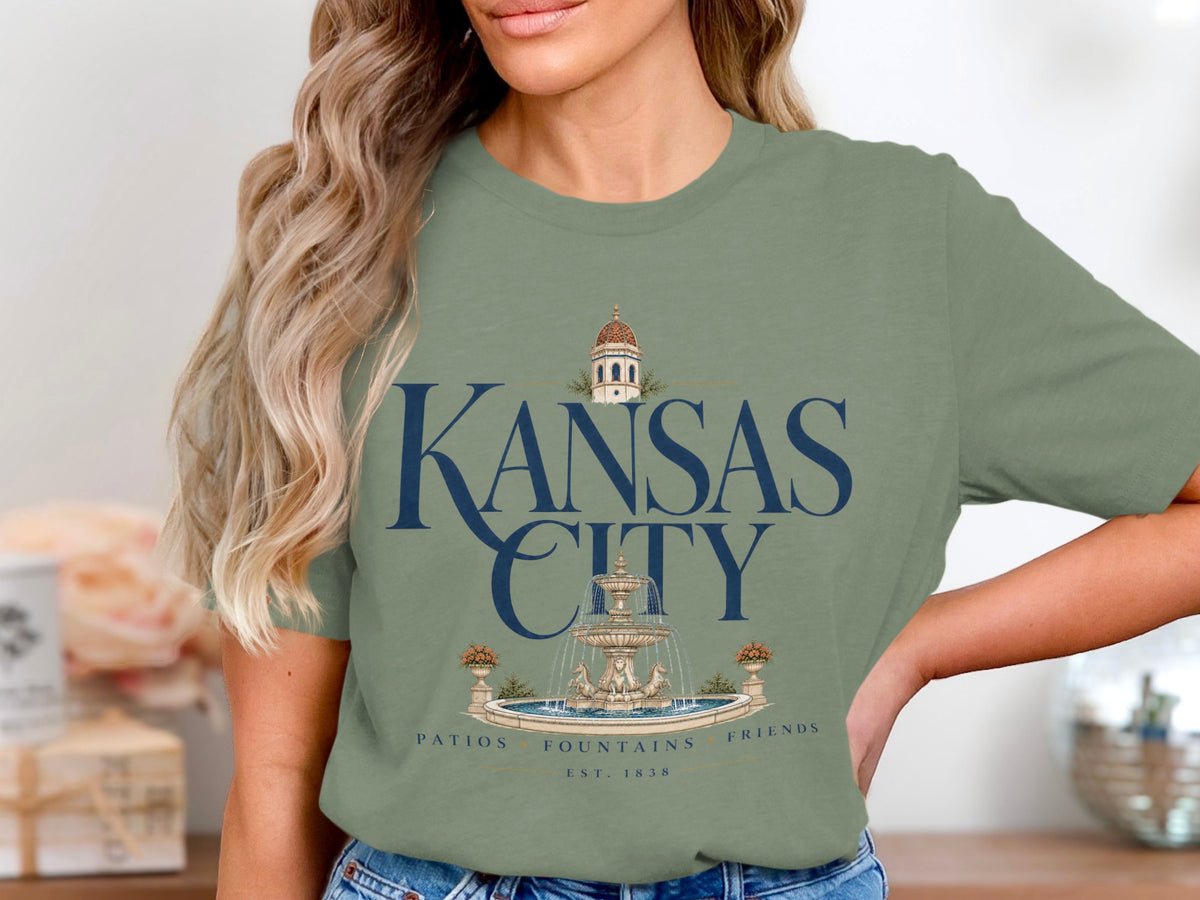 Green t-shirt with "Kansas City" text, fountain illustration, and "Patios Fountains Friends Est. 1838".