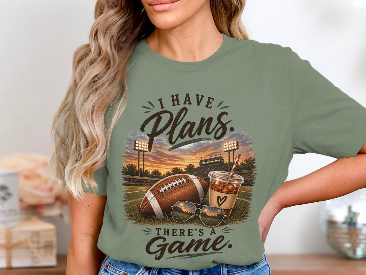 Green t-shirt with "I Have Plans. There's A Game." text, football, sunglasses, and drink.