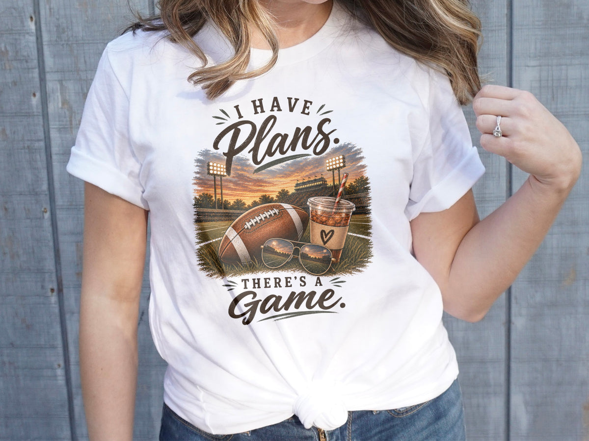 White t-shirt with graphic "I have plans. There's a game." and football scene.