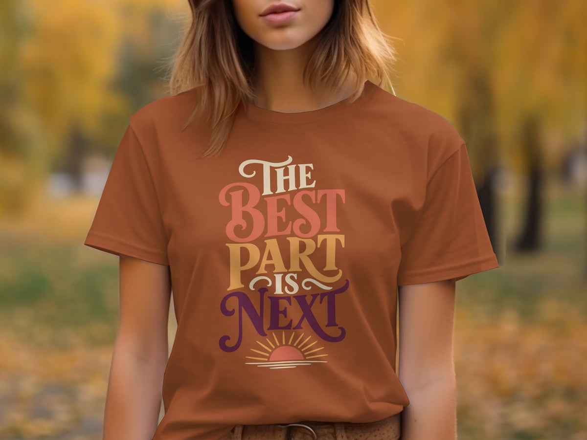 Brown t-shirt with text "The Best Part Is Next" and a sunrise graphic.