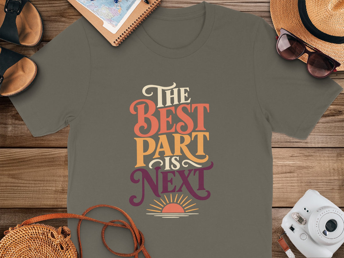 Grey t-shirt with text "The Best Part Is Next" and a sunset graphic.