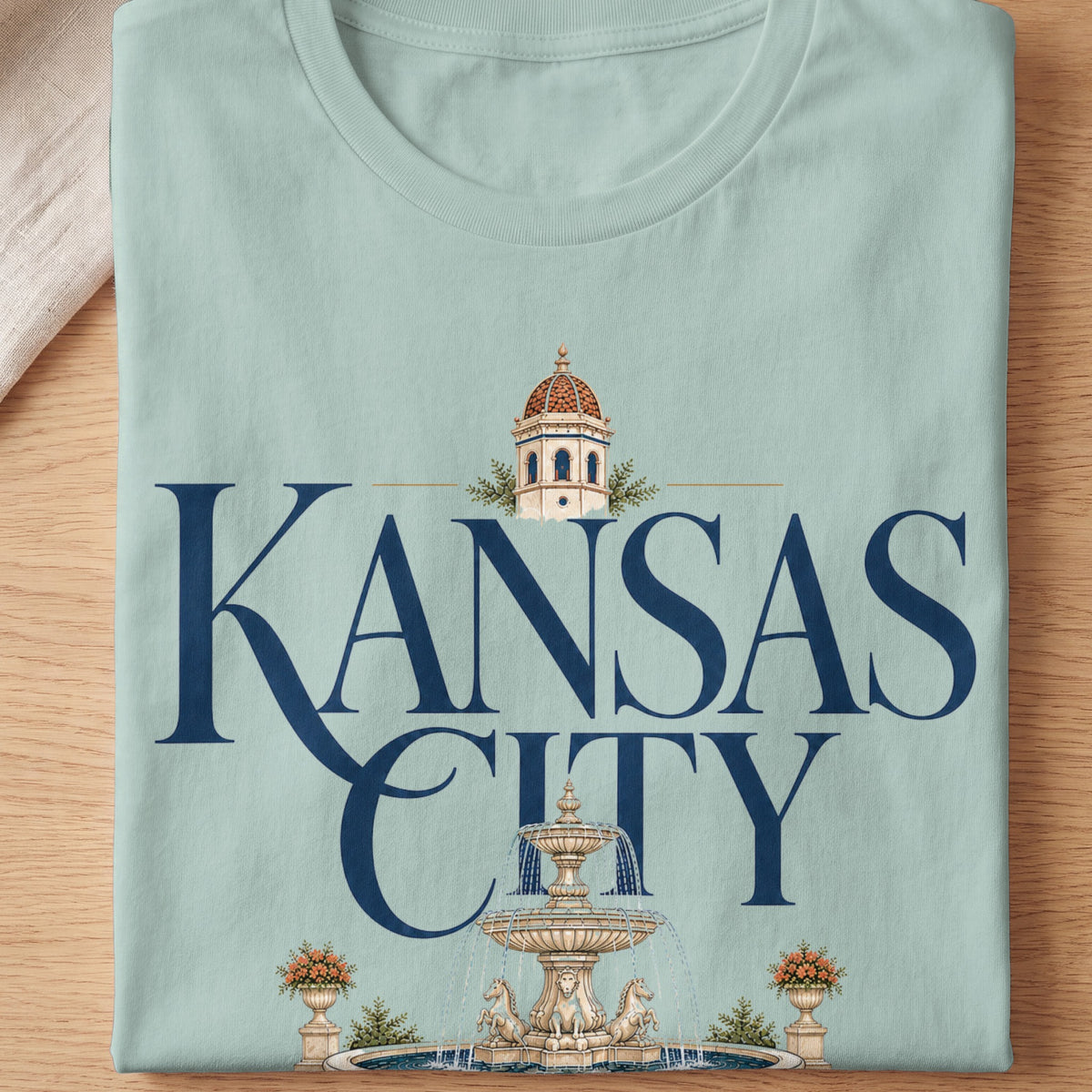 Light blue t-shirt with "KANSAS CITY" text, a dome tower, and a fountain.