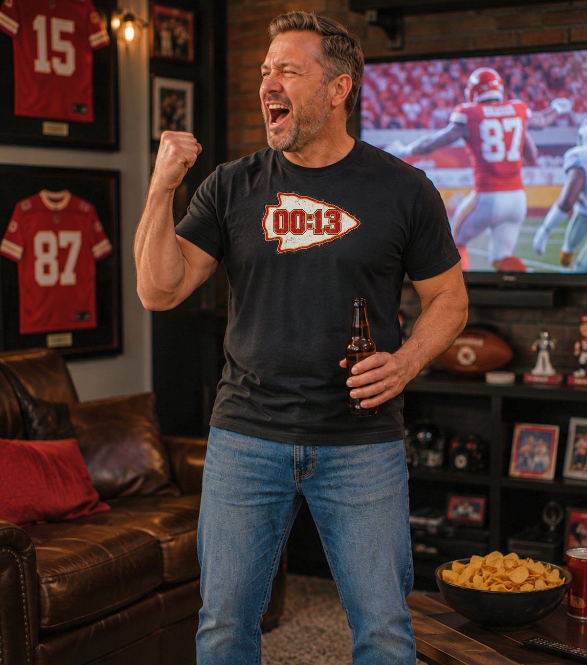 Man in a black t-shirt with arrowhead logo and "00:13" watches football on TV.
