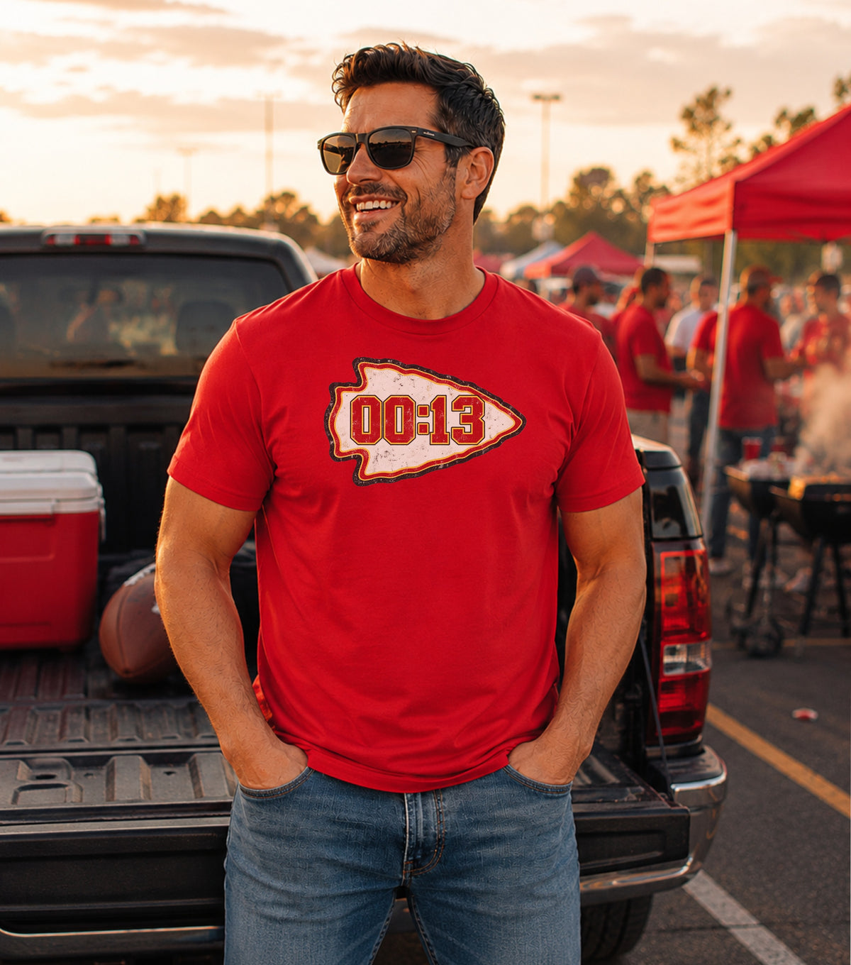 Man in red t-shirt with "00:13" arrowhead logo stands by truck.