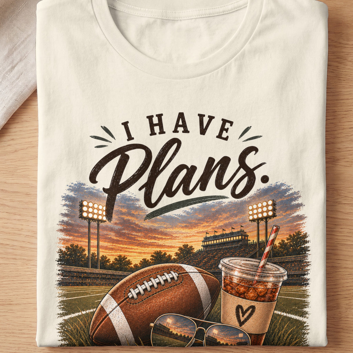 T-shirt graphic: "I Have Plans" text, football, drink, sunglasses, stadium at sunset.