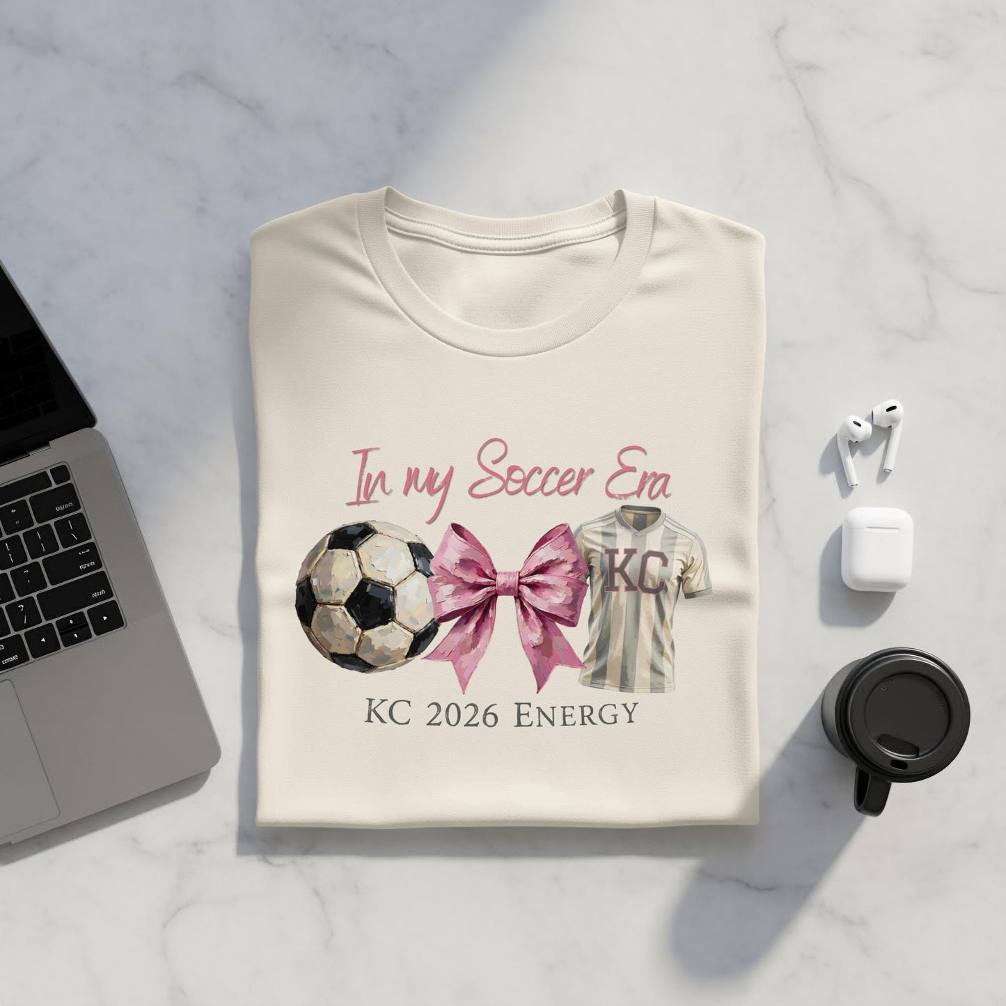 Cream t-shirt with "In my Soccer Era KC 2026 Energy" and soccer ball graphic.
