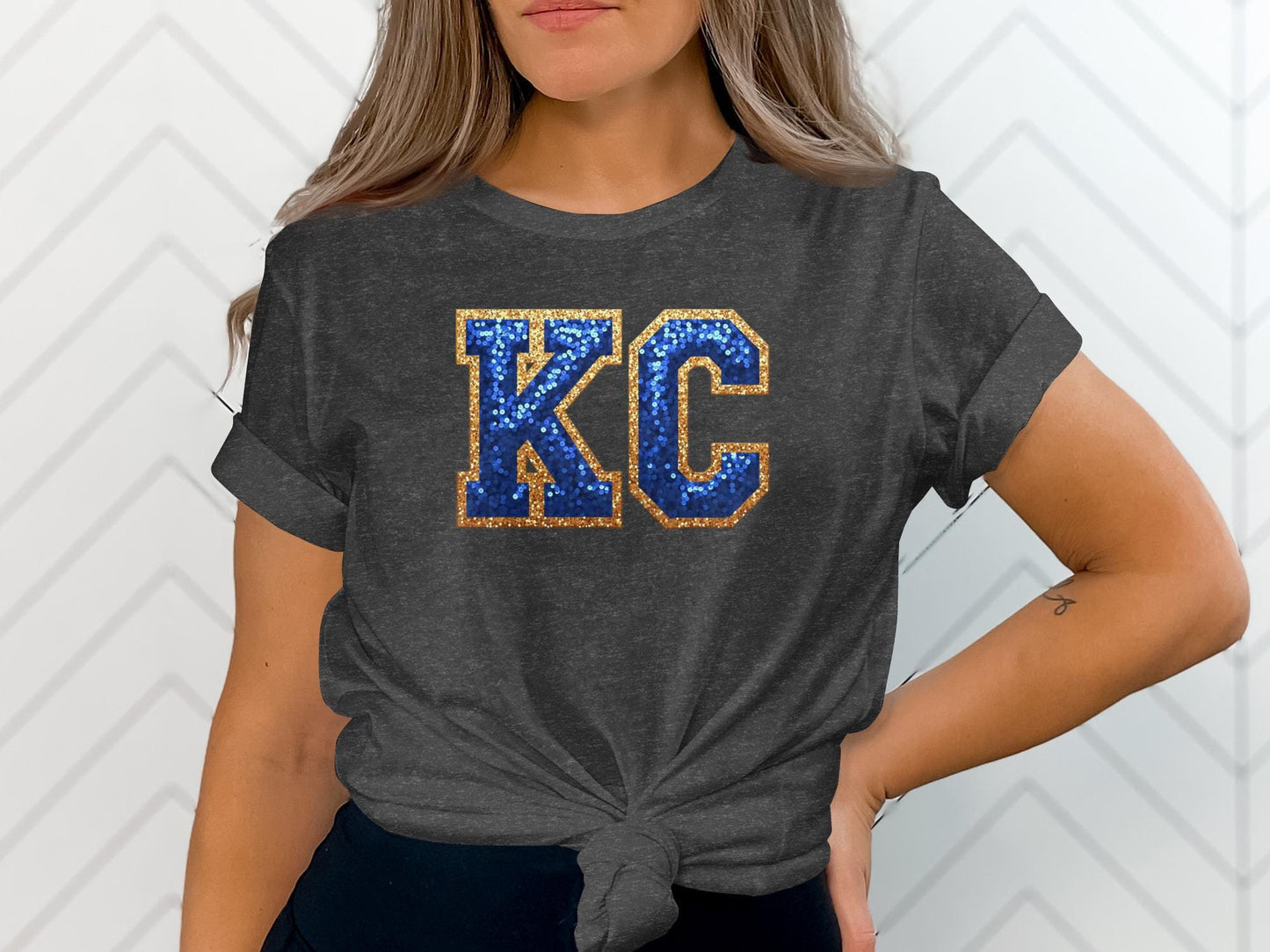 Dark grey t-shirt with glittery blue "KC" graphic, tied at waist.
