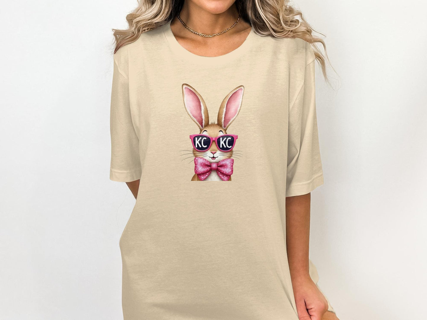 Tan t-shirt with cartoon bunny wearing pink sunglasses and bow tie.