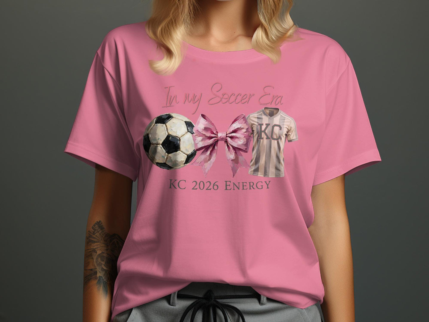 Pink t-shirt with "In My Soccer Era KC 2026 Energy" and soccer ball graphic.