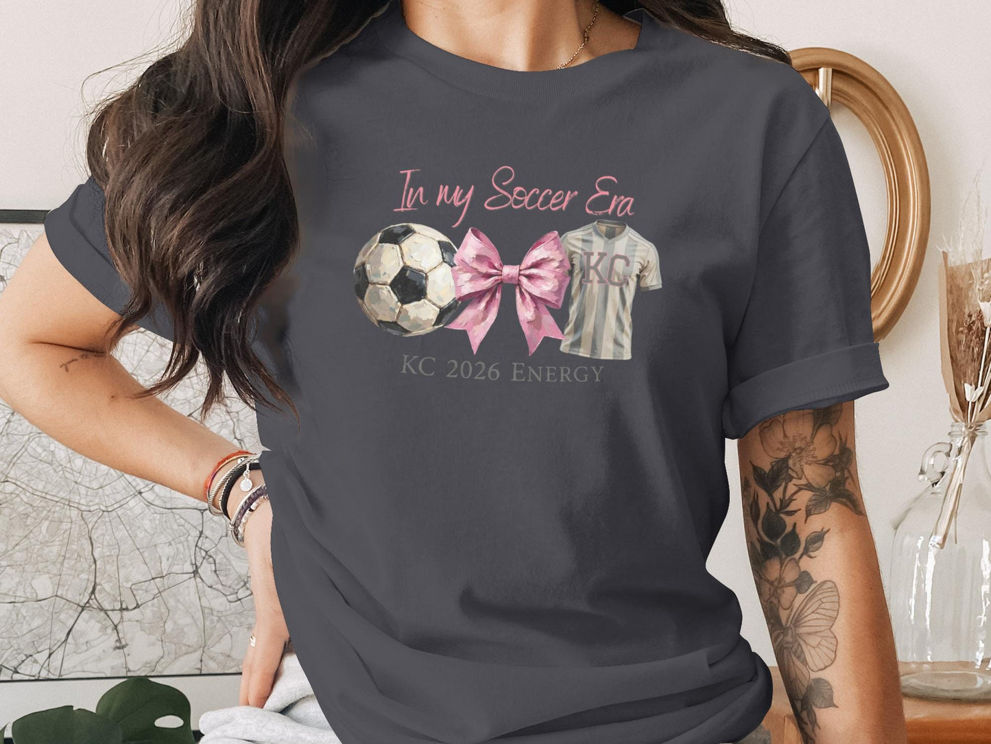 Gray t-shirt with soccer ball, pink ribbon, and "In my Soccer Era KC 2026 Energy" text.