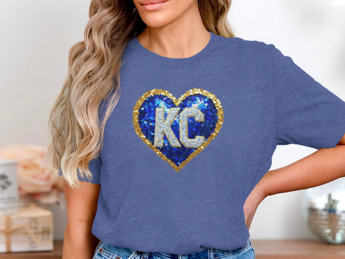 Blue t-shirt with a gold sequined heart and "KC" lettering.