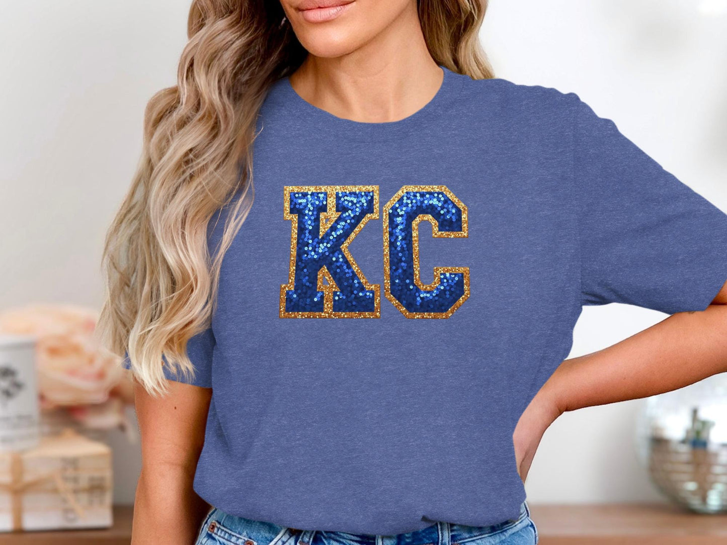 Blue t-shirt with gold glitter "KC" lettering on a woman's chest.
