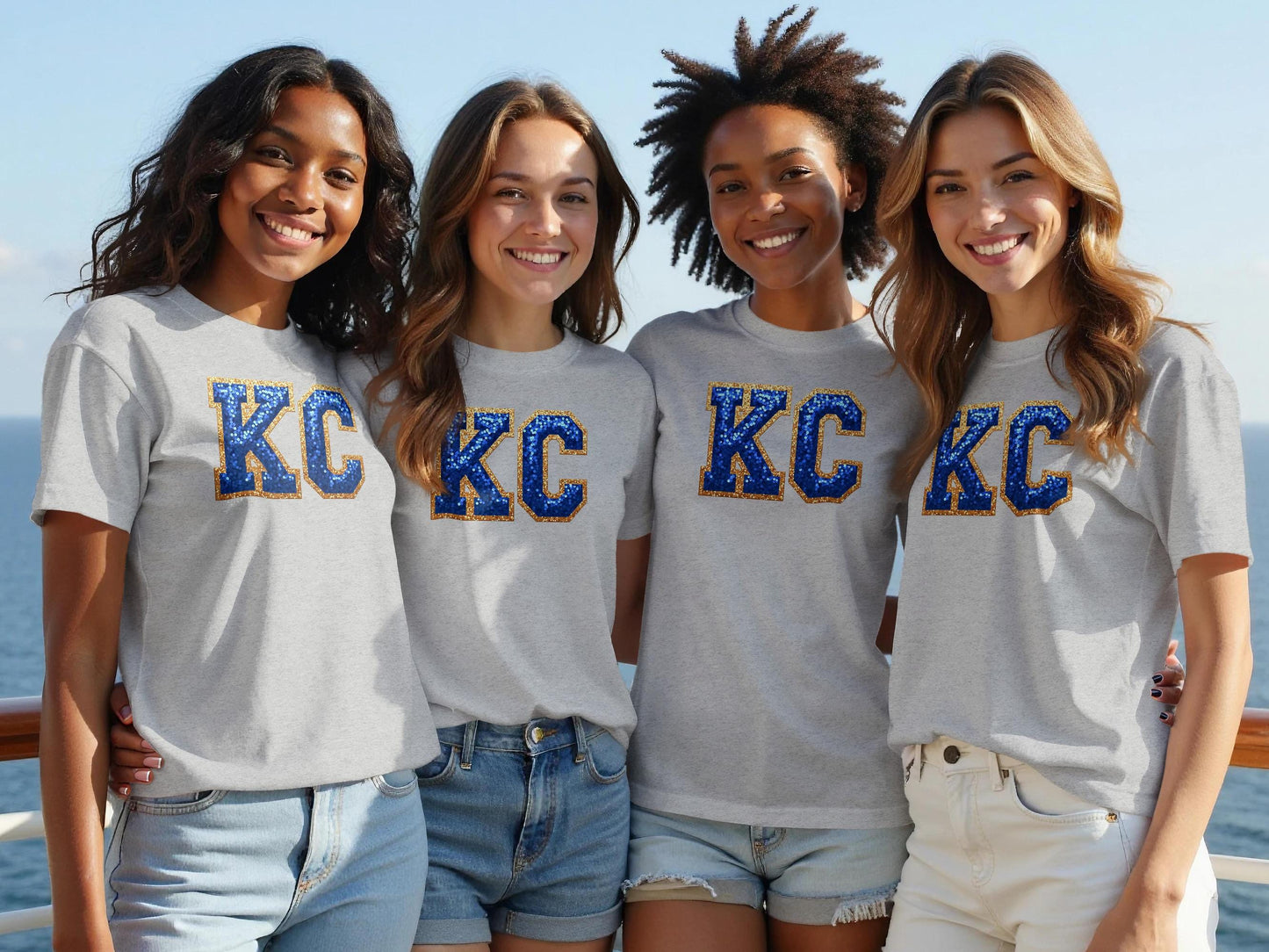 Four young women in KC graphic t-shirts smiling outdoors.