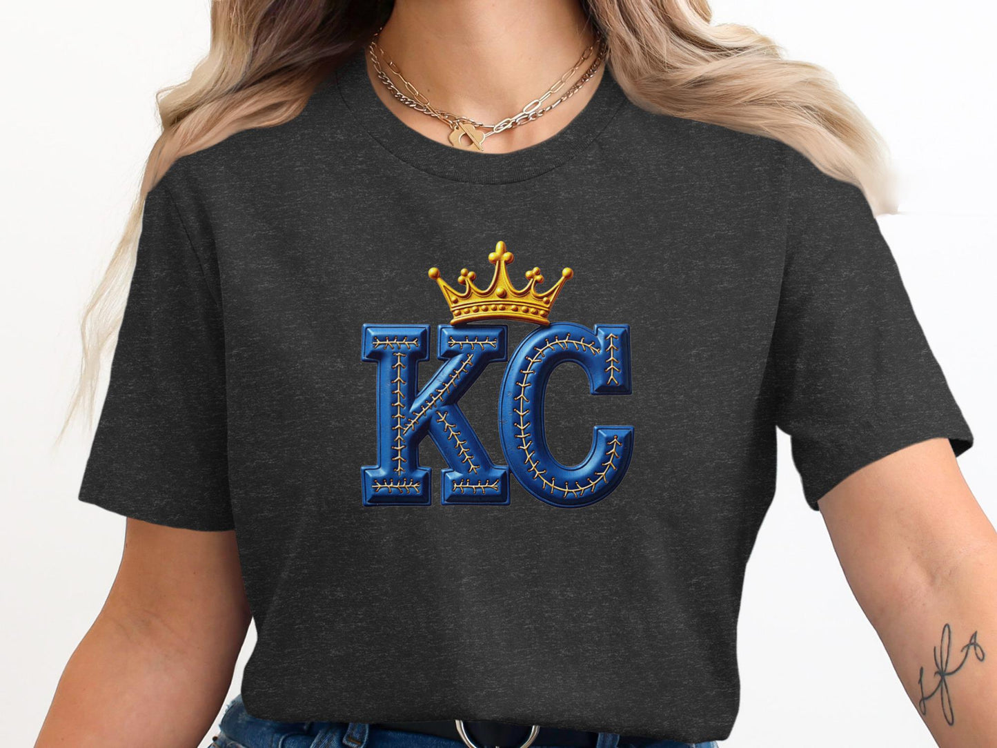 Dark t-shirt with large, textured "KC" letters topped with a golden crown.