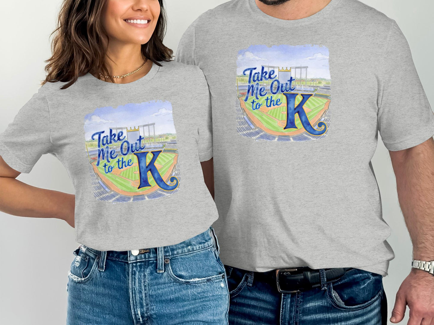 Two people wearing gray t-shirts with "Take Me Out to the K" baseball stadium graphic.