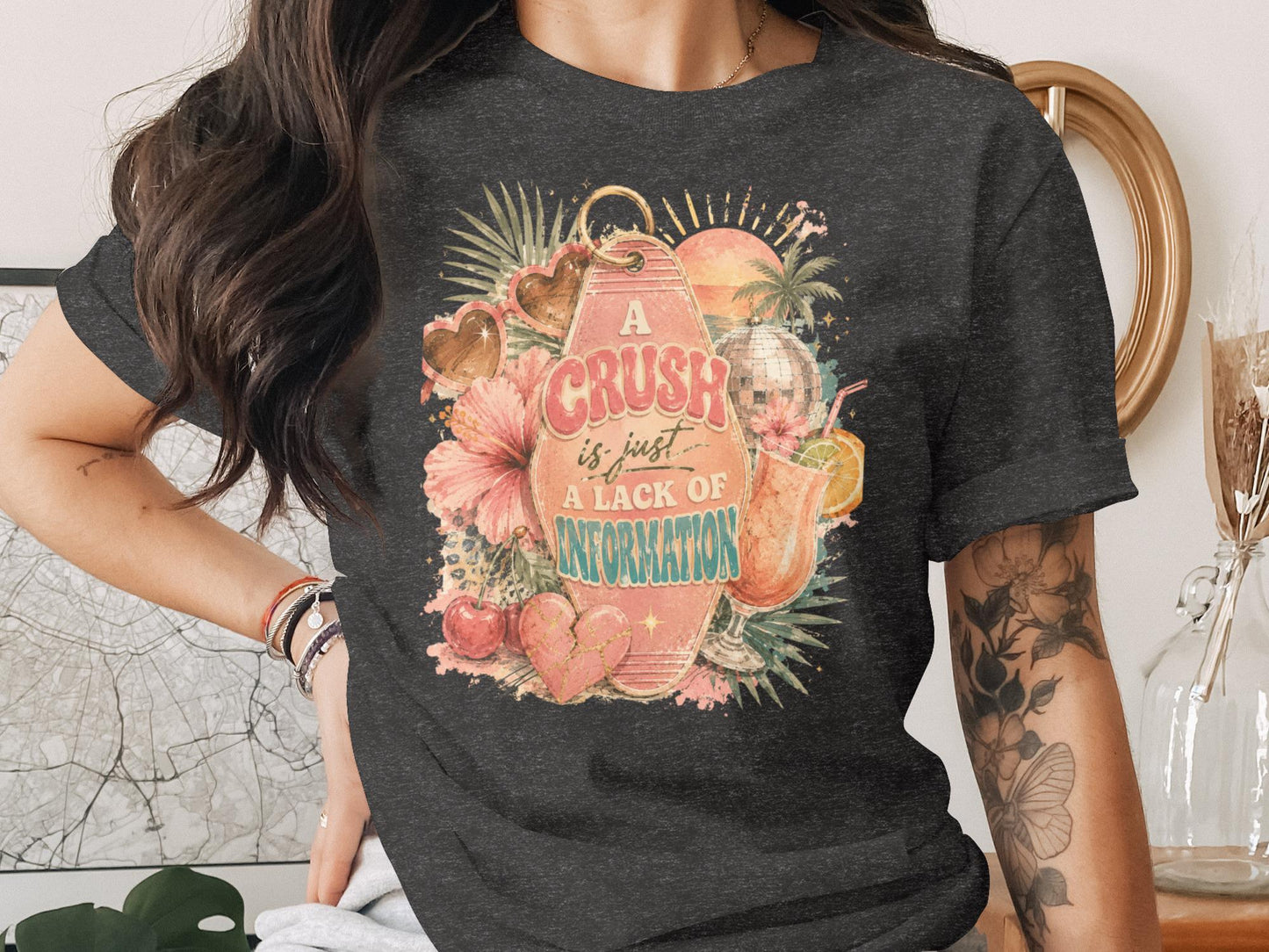 Dark t-shirt with distressed graphic of a keychain, flowers, hearts, disco ball, and cocktail.
