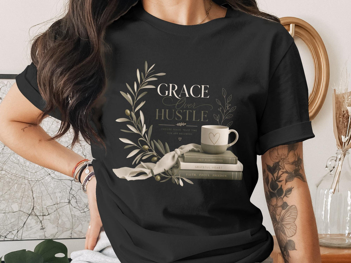 Black t-shirt with "Grace Over Hustle" design and stack of books.