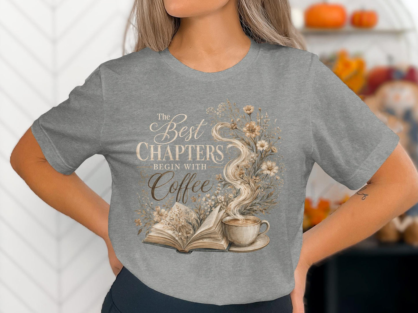 Grey t-shirt with a design of an open book, coffee cup, and floral wreath with text.