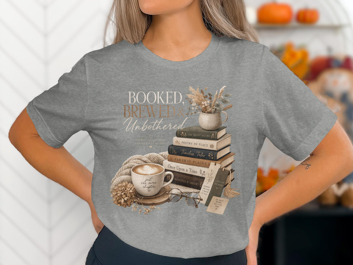 Grey t-shirt featuring "BOOKED, BREWED, Unbothered" with books, coffee, and glasses.