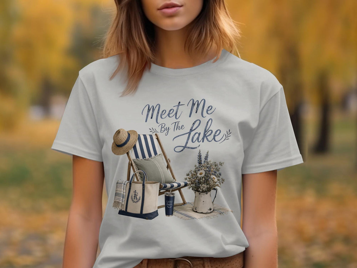Peach t-shirt graphic with "Meet Me By The Lake" text, beach chair, and tote bag.