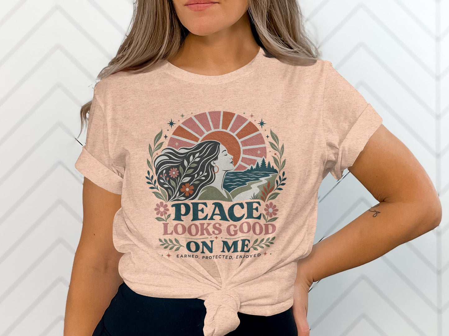 T-shirt graphic with woman's profile, sun, nature, and text "Peace Looks Good On Me".