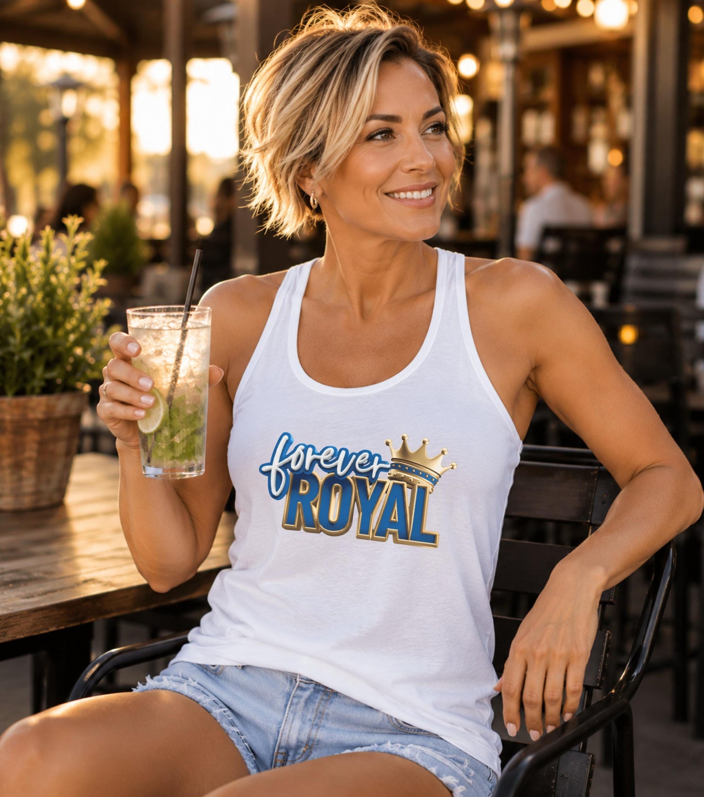 Woman in white tank top with "Forever Royal" and crown graphic, holding a drink.
